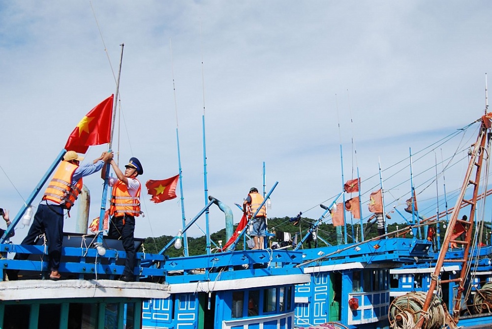 Cảnh sát biển trao tặng và thay cờ Tổ quốc cho các tàu cá ngư dân.